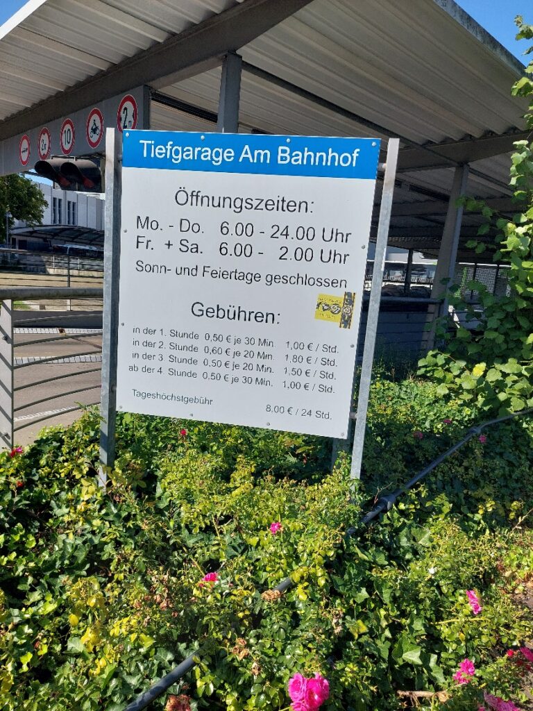 Hinweisschild „Tiefgarage Am Bahnhof“ mit Öffnungszeiten: Mo-Do 6-24 Uhr, Fr-Sa 6-2 Uhr, Sonn- und Feiertags geschlossen. Es sind Gebühren für unterschiedliche Laufzeiten angegeben.